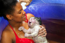 Woman holding her new born baby in a birthing pool