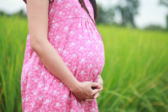 Pregnant woman outside in a pink dress