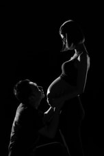 Man kneeling and looking up at a pregnant woman who is standing