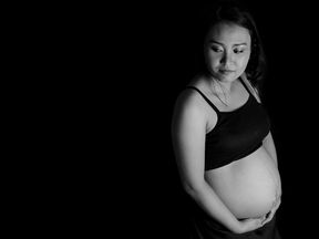 Pregnant woman wearing a crop top.  Standing black and white image